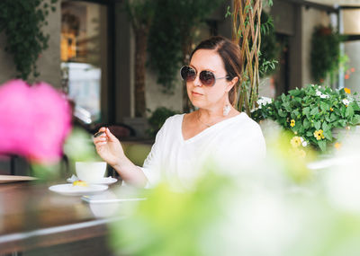 Portrait of woman holding sunglasses at restaurant table