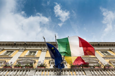 Low angle view of flags on building against sky