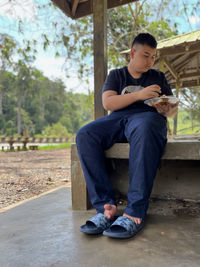 Young man using mobile phone while sitting on footpath