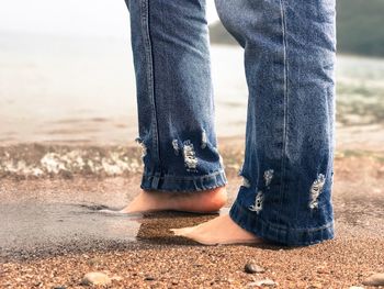 Low section of woman walking on sand at beach