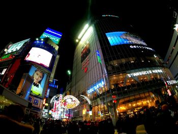 People on illuminated street amidst buildings at night