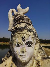 Close-up of 'mahadev' statue against clear blue sky