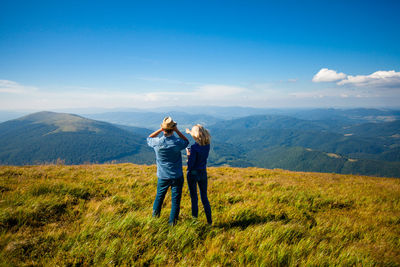 Rear view of friends on mountain against sky