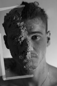 Portrait of young man with dirty face against gray background