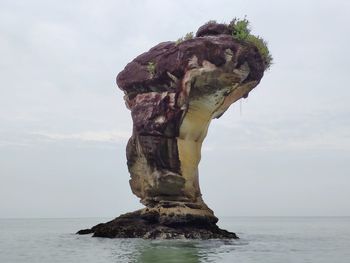 Rock formation in sea against sky, snake head