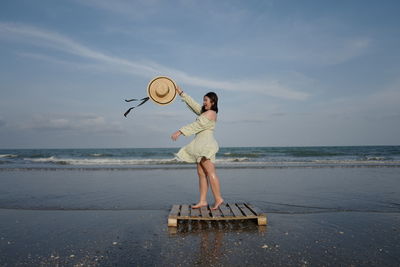 Man holding umbrella on beach against sky