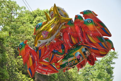 Low angle view of multi colored umbrellas hanging on tree against sky