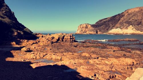 Scenic view of sea and mountains against clear sky