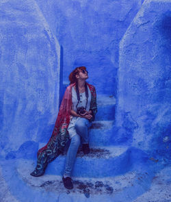 Full length of young woman sitting on steps outdoors