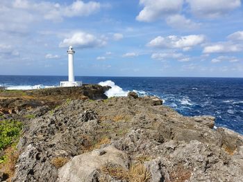 Lighthouse on rockface by sea against sky, okinawa, japan