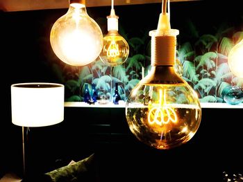 Close-up of illuminated light bulb hanging on table at home