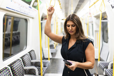 Young woman using mobile phone in subway train