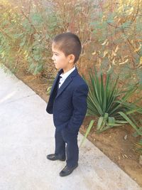 Side view of boy standing against plants