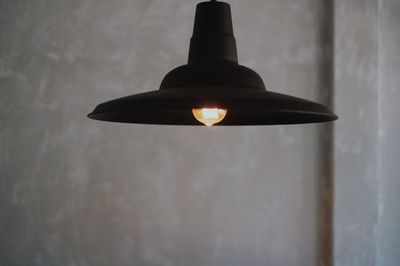 Low angle view of illuminated lamp hanging against wall