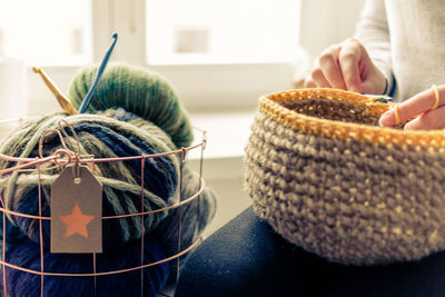 Midsection of woman knitting basket at home