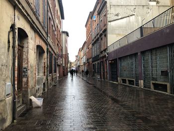 People walking in alley amidst buildings