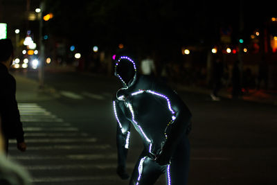 Man standing on illuminated street at night