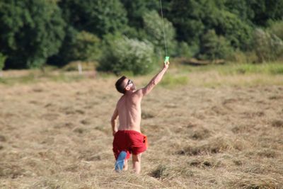 Full length of shirtless man standing on field