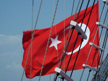 Low angle view of turkish flag waving against sky