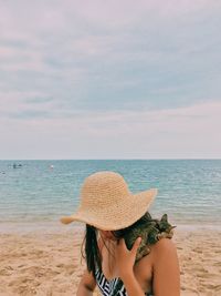 Woman wearing hat on beach against sky