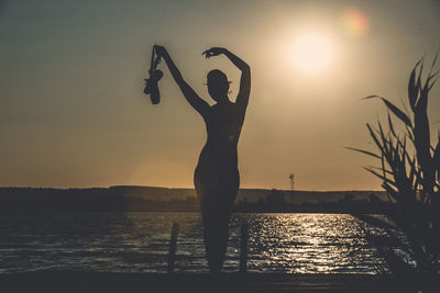 Silhouette man standing by sea against sky during sunset