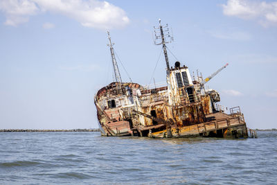 Abandoned ship in sea against sky