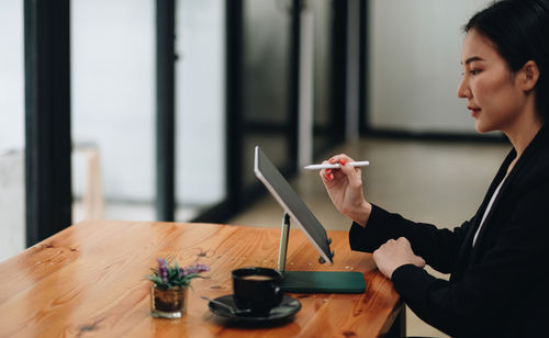 Side view of man using mobile phone while standing in office