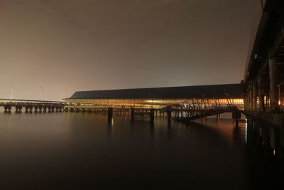 Illuminated bridge over water at night