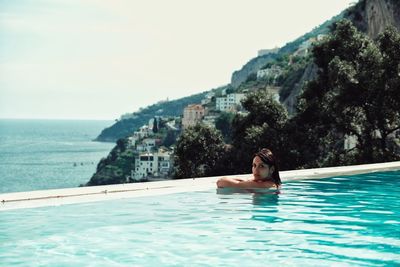 Man relaxing in swimming pool against sea