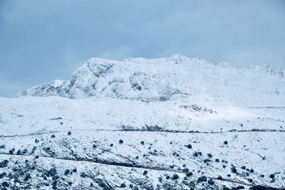 Snow covered landscape against blue sky