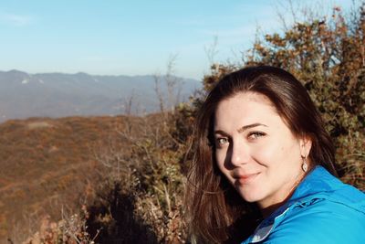 Portrait of smiling young woman against sky