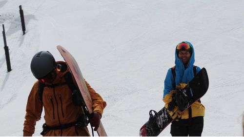 Friends with snowboards walking on snow