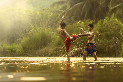 Full length of shirtless boys playing in water