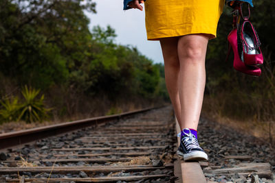 Low section of woman walking on railroad track