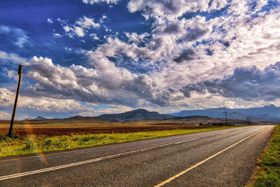 Road passing through land against sky