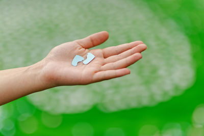 Cropped hand of woman holding paper footprints outdoors