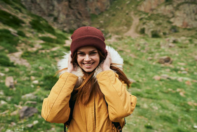 Portrait of young woman standing against trees