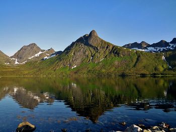 Scenic view of lake and mountains against clear blue sky