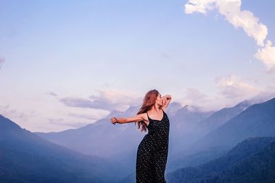 Woman standing on mountain against sky