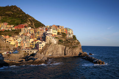 Buildings at sea shore at manarola against clear blue sky