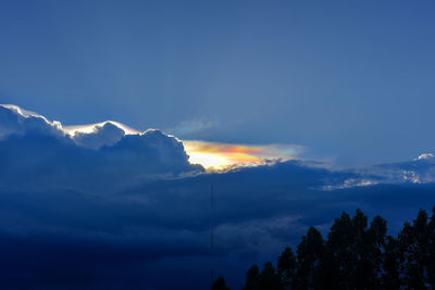 Low angle view of sunlight streaming through clouds