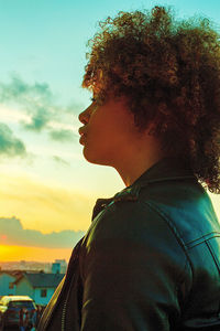 Portrait of young woman looking away against sky during sunset