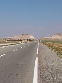 Empty road against clear blue sky