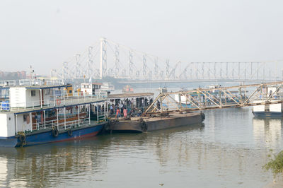 Fishing boats on pier over river against sky