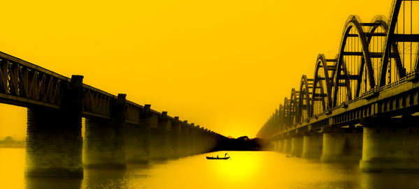 Bridge over river against sky during sunset