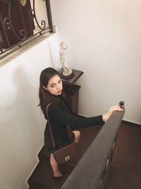 Portrait of young woman sitting on wall