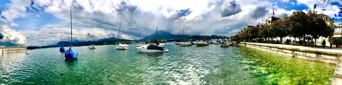 Panoramic view of boats moored in water against cloudy sky