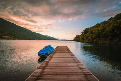 Lake mergozzo at dawn with wooden jetty in the foreground and colored clouds. without people