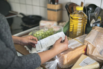 Person checking receipt from supermarket during inflation with rise in price of food and consumer products