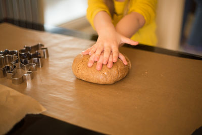 Midsection of woman holding dough on kitchen counter